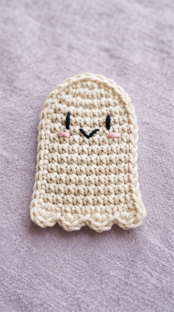 Ivory crochet ghost appliqué with pink cheeks and a scalloped bottom.